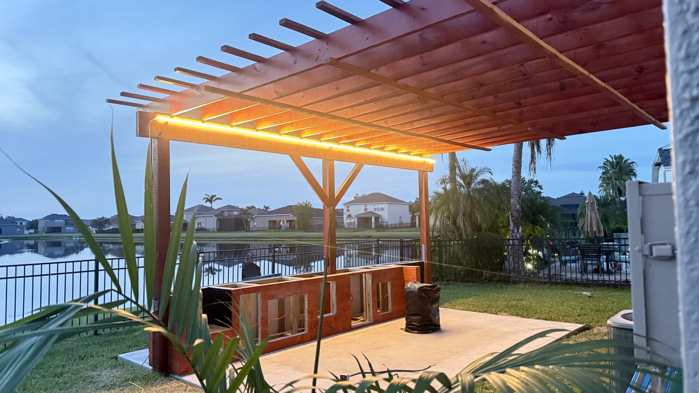 Covered pergola with warm integrated lighting over a waterfront deck